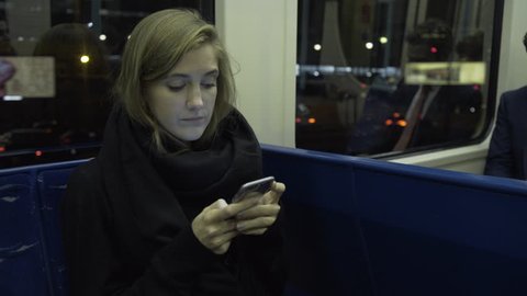 Young adult female on train using smart phone