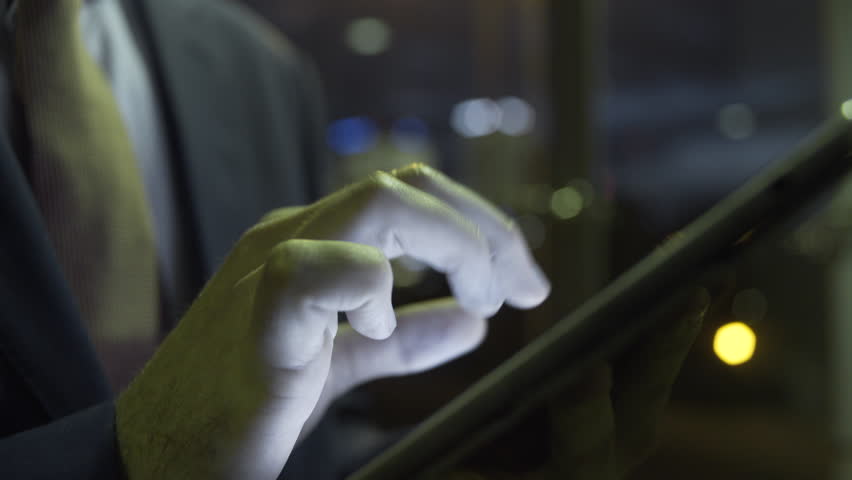 Business male on digital tablet in evening at business district