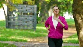 A young woman runs in a beautiful green park in slow motion, The Slow Motion of Running in a Nature, Slow Motion Video Clip