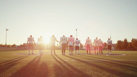 A football team walking away from the camera in slow motion, with lens flare Vídeo Stock