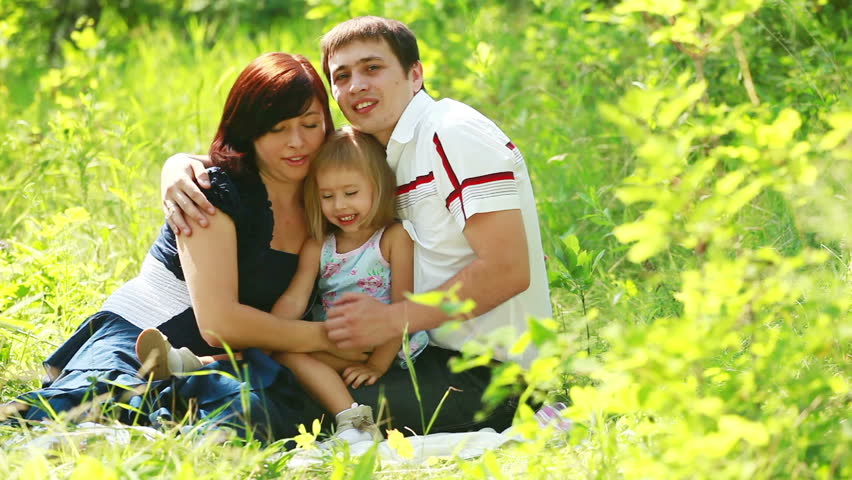 Smiling family in the grass looking at camera 