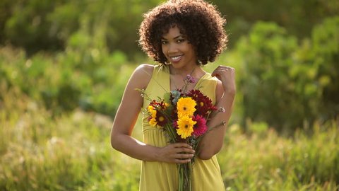 Young woman holding flowers in field