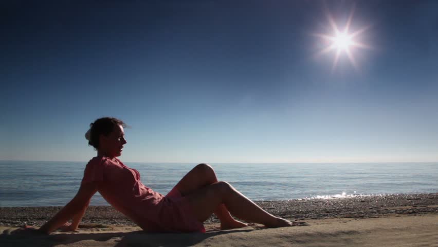 Woman sitting on beach sand at sunny day, sea behind | Shutterstock HD Video #1256917
