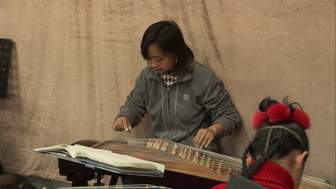 Beijing, China - February 2008: Chinese teacher playing the guzheng, a Chinese musical zither, in classroom, Beijing, China.