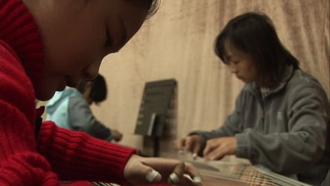 Beijing, China - February 2008: Music students strumming the guzheng zither, a traditional Chinese string instrument, with their teacher. Beijing, China.