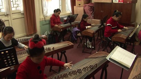 Beijing, China - February 2008: A teacher and her students playing the guzheng, a Chinese string instrument, in a school music class. Beijing, China.