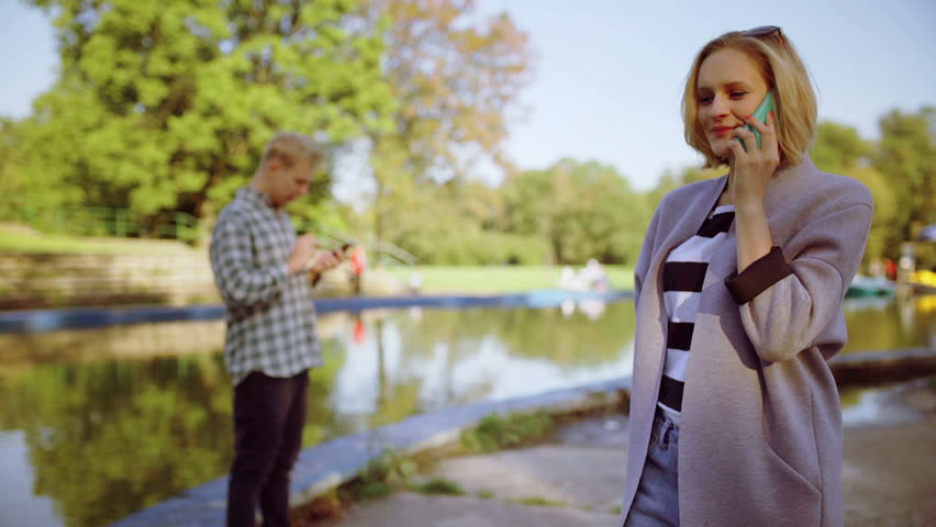Girl chatting on cellphone in the park next to the river
