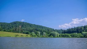 This video shows a beautiful surrounding nature of the lake. The day is sunny and wonderful, the sun is reflecting in the lake. Wide-angle shot.