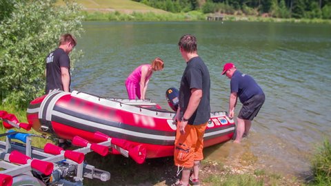 EVENT LUKOVICA JUNE 2015: A few people are pushing a rubber boat into the lake on a beautiful and sunny day. Close-up shot.