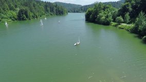EVENT LUKOVICA JUNE 2015:In this video, we can see a beautiful green lake with it surrounding forests. The day is sunny and bright. We can also see the boats on the shore and two small houses.