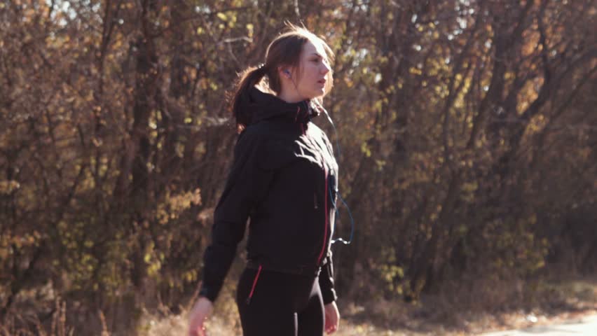 The girl does exercises in autumn park on a racetrack