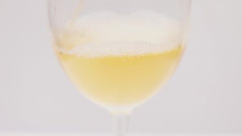 vino bianco, vino Moscato viene versato in un bicchiere su uno sfondo bianco 