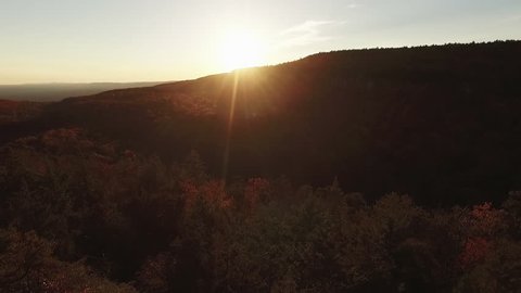 Aerial of female hiker looking out over mountain valley at sunset