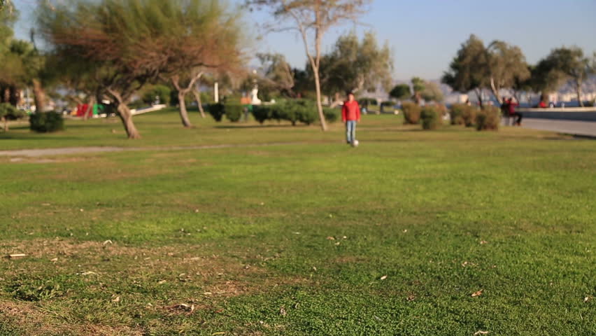 Young boy kicking ball in the grass outdoors