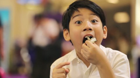 Happy asian boy eating japanese food.