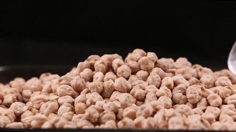 Chickpeas taken with metal spoon isolated in black background