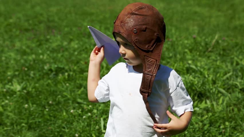 Cute boy in the old helmet pilot playing with paper plane