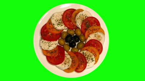 Pieces of sheep cheese and tomatoes, green and black olives on plate rotating on green screen, top shot, loop (ultra hd 3840x2160)