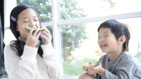 Cute asian children eating melon