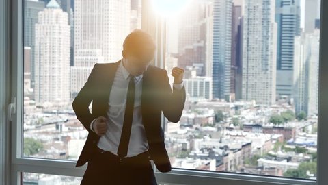 young successful business man dancing in modern office. cityscape skyline background