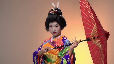 Japanese geisha performer posing in Studio with umbrellas, slow motion