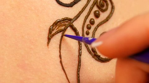 Drawing process of henna mehendi ornament on woman's back, close up