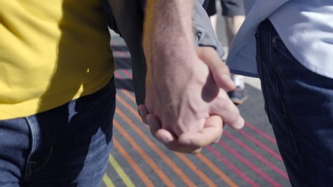 Closeup Of Gay Couple Holding Hands, Walking Toward Camera, Across Rainbow Colored Crosswalk In San Francisco Stock Video