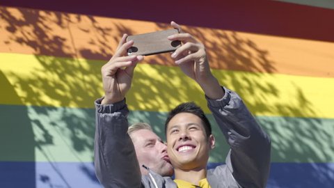 Cute Gay Couple Pose For Photos In Front Of Gay Pride Rainbow Wall  Video stock
