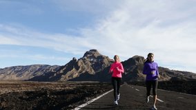 Fitness young women jogging together running on mountain road. Female runners are in sportswear. Multiethnic joggers are living healthy lifestyle.