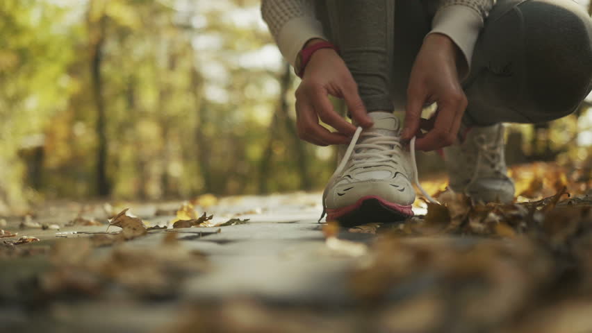 Young sporty woman preparing to run in a beautiful autumn forest, wellness concept.