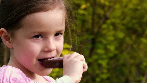 A little girl eats a popsicle in a park - part 1