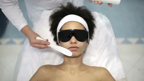 Health and beauty: African american woman have a face whitening procedure. Whitening session with high energy beam of light and chemicals applied to whiten face.