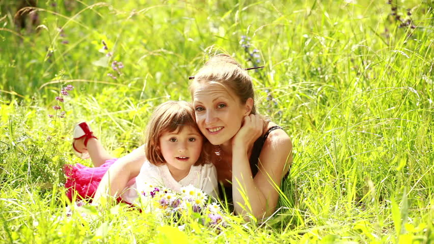 Mother and daughter lying in the grass. Looking at camera  