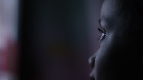 4K Profile of child's face watching a colourful screen in the dark, in slow motion