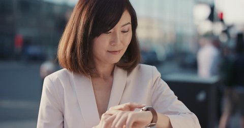 Slow Motion Portrait of beautiful Japanese woman using smart watch sharing social media connection in city real people series