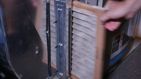 Replacing a dirty air filter in a household furnace unit.	