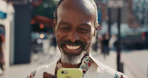 Slow Motion Portrait of mature african american man using smart phone sharing social media connection in city real people series