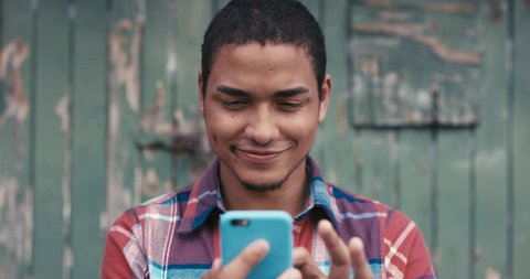 Slow Motion Portrait of mixed race man smiling using smart phone sharing social media connection in the city urban face normal people series