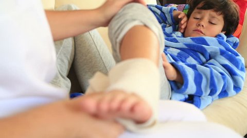 Nurse bandaging little boy ankle