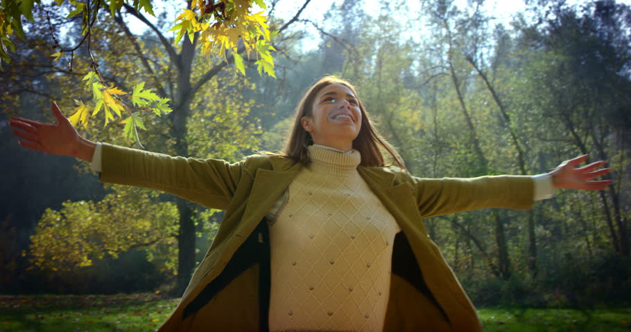 Super slow motion of young caucasian brunette woman dressed in a jacket spinning of joy on a scenic autumn landscape on a sunshine in 4k (close up )