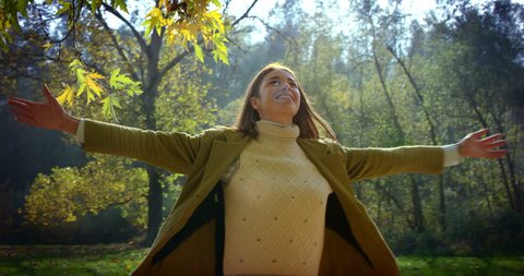 Super slow motion of young caucasian brunette woman dressed in a jacket spinning of joy on a scenic autumn landscape on a sunshine in 4k (close up )