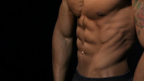 Close up man showing a perfect ABS. Muscular man bodybuilder. Man posing on a black background, shows his muscles. Bodybuilding, posing, black background, muscles - the concept of bodybuilding