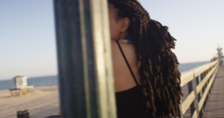 Two black women friends rear view at beach pier with close up of long hair
