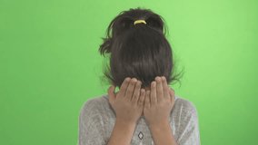 Girl Crying - A young female kid covers her face and cries. Shot against a green screen studio backdrop.