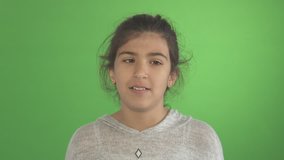 Girl Acting Silly - A young little girl acts weird and funny as she rolls her eyes in a comedic way in front of a green screen studio background.