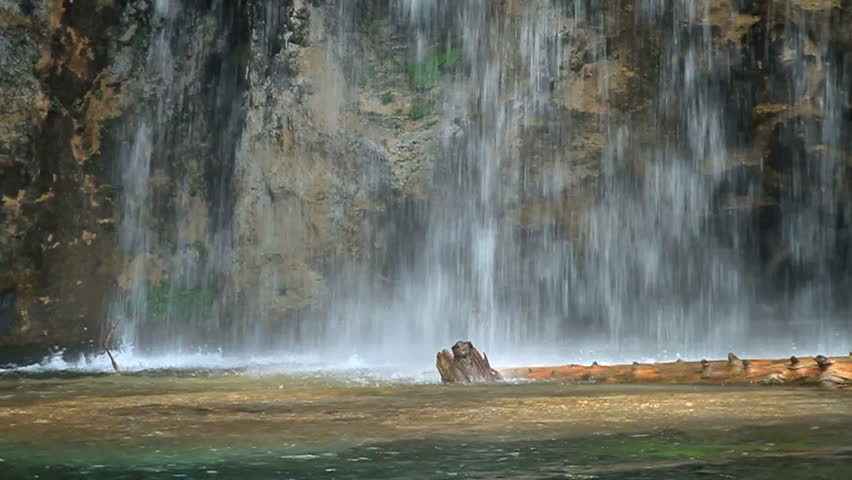 Slow motion of water falling into a lake at the base of a waterfall. 