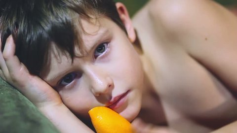 teenager  boy lying sideways holding licked orange peel