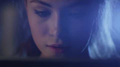 Portrait shot of a beautiful young girl looking a working tablet in the dark. Shot on RED Cinema Camera in 4K (UHD).