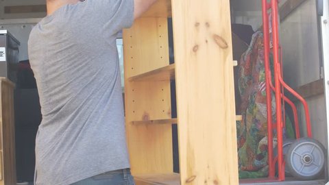 Man sets down bookshelf in moving truck