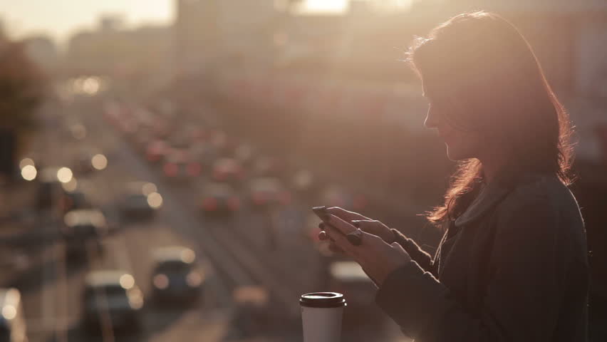 Beautiful young girl uses a smartphone on a city bridge  | Shutterstock HD Video #12701051